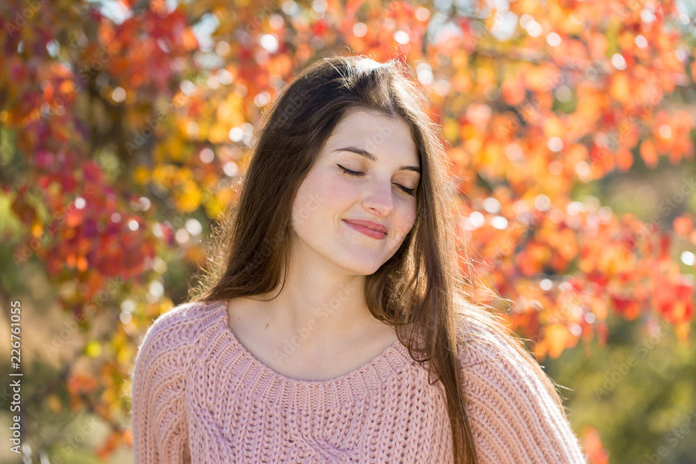 Portrait of pretty young woman in stylish knitted sweater standing on the golden autumn forest on sunny day Portrait of pretty young woman in stylish knitted sweater standing on the golden autumn forest on sunny day