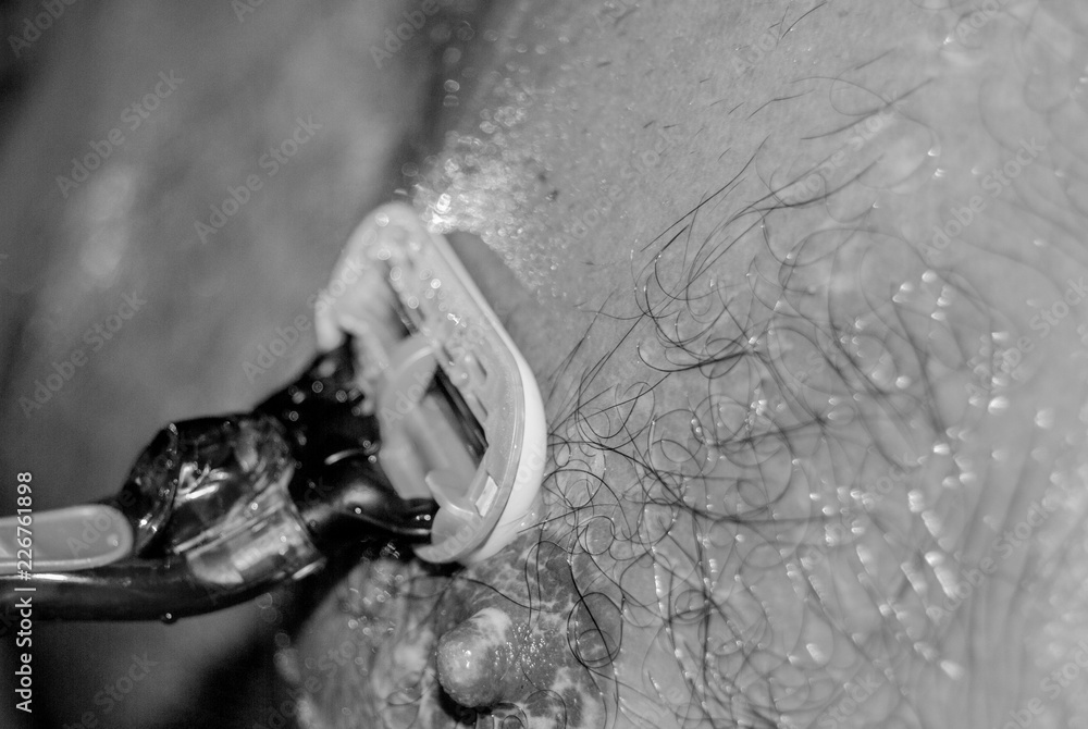 Man with a razor cutting his hair on chest covered with shaving foam Man with a razor cutting his hair on chest covered with shaving foam