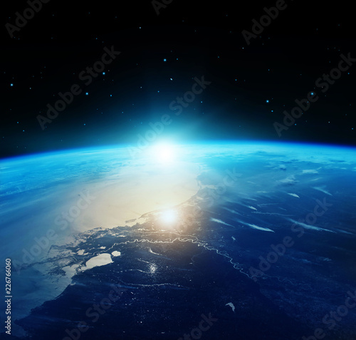 View of blue planet Earth with sun rising from space. Elements of this image furnished by NASA.