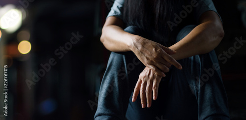 PTSD Mental health concept. Post Traumatic Stress Disorder. The depressed woman sitting alone on the floor in the dark room background. Film look.