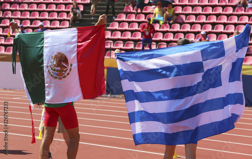 Athletes with mexican and greek flag on the stadium photo