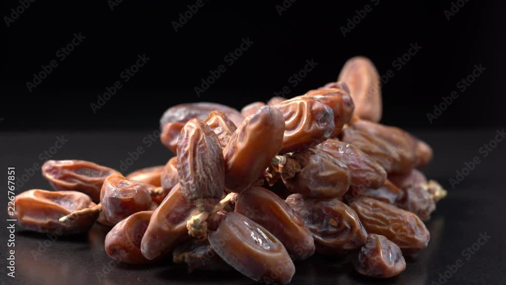 Dried date fruit rotates, background dates, close up. Food background. Gastronomy concept, organic food. Macro dates fruit on black background Dried date fruit rotates, background dates, close up. Food background. Gastronomy concept, organic food. Macro dates fruit on black background