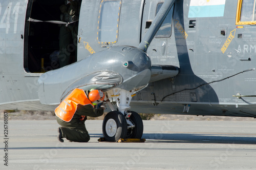 Mechanic of a military sea king helicopter doing a maintenance inspection on a principal landing gear, ground check