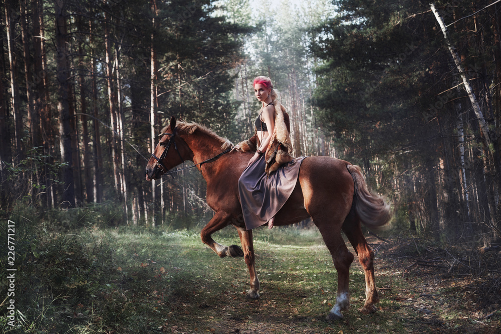 Woman on a horse in the fall. Creative bright pink makeup on the girl face, hair coloring. Portrait of a girl with a horse. Horseback riding in the autumn forest. Autumn clothes Woman on a horse in the fall. Creative bright pink makeup on the girl face, hair coloring. Portrait of a girl with a horse. Horseback riding in the autumn forest. Autumn clothes