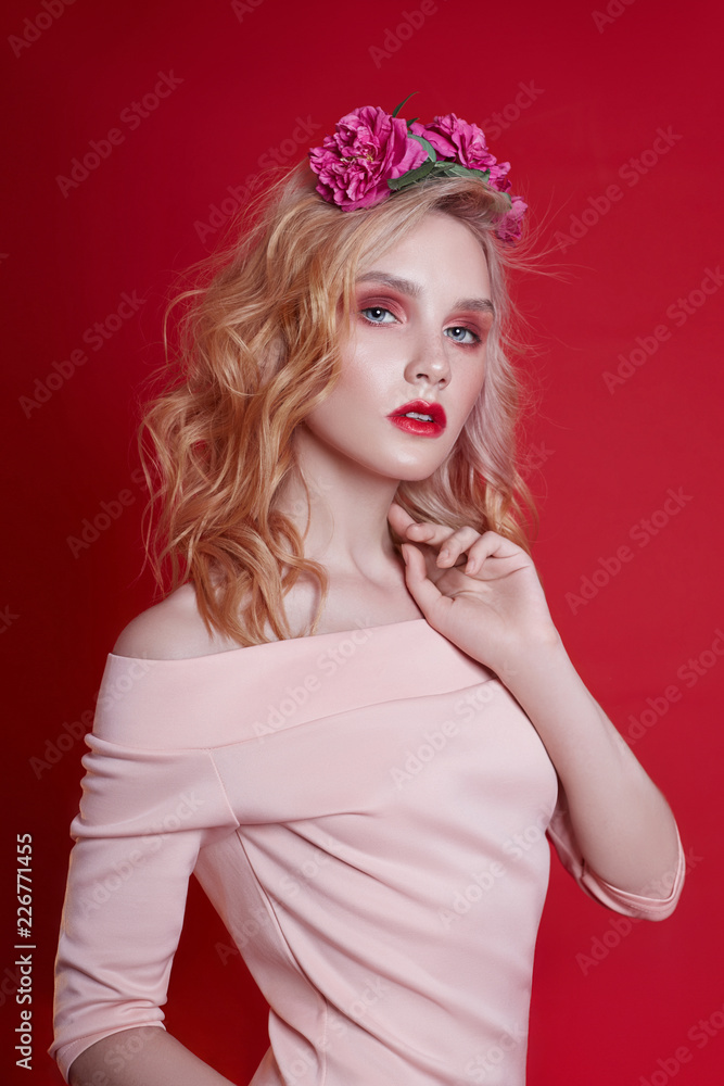 Portrait of sexy fashion beautiful blonde woman with bright makeup posing on red crimson background. Slender blonde girl, perfect figure and long hair. Clean perfect face skin
