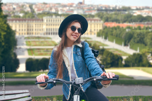 A beautiful european girl riding a bicycle on a city background