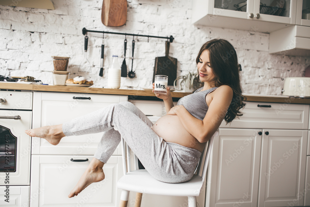 Beautiful pregnant woman in kitchen with cup of milk Beautiful pregnant woman in kitchen with cup of milk