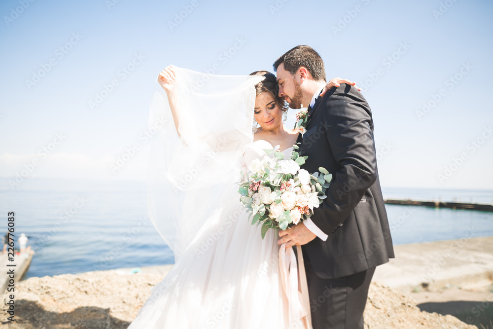 Happy and romantic scene of just married young wedding couple posing on beautiful beach Happy and romantic scene of just married young wedding couple posing on beautiful beach