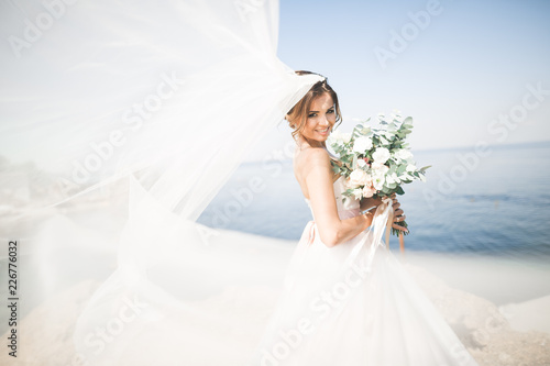 Lovely bride in white wedding dress posing near the sea with beautiful background
