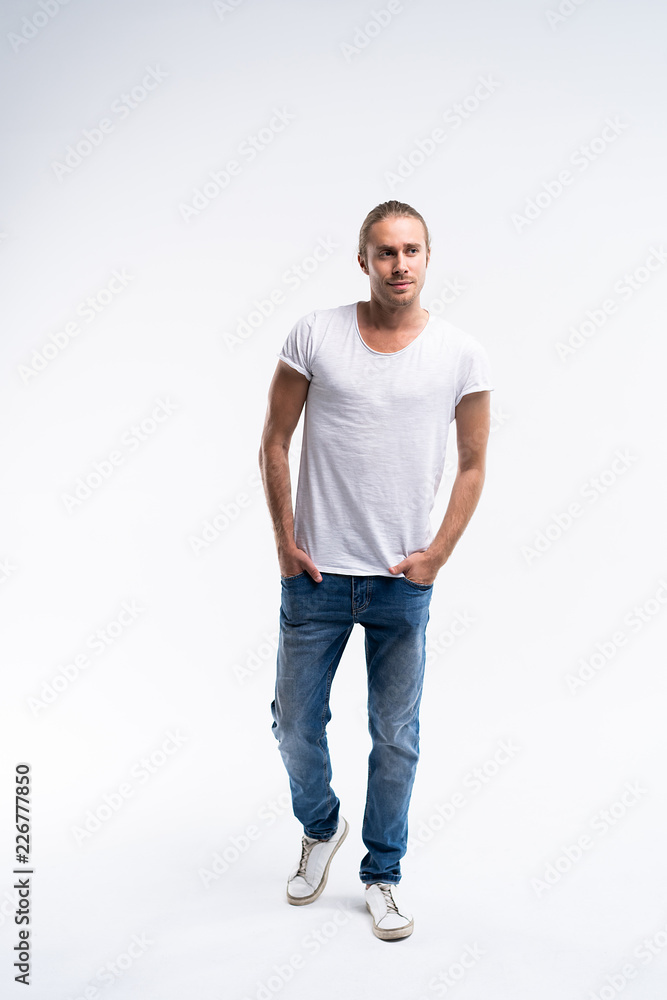 Full length of a cute young man in jeans and t-shirt looking at the camera, against white background. Full length of a cute young man in jeans and t-shirt looking at the camera, against white background.