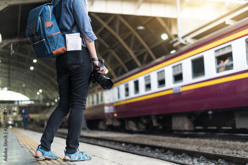 Back side of Young Asian traveling women holding camera and map traveling by train at Bangkok railway station, Thailand, traveler, tourist and photography concept Back side of Young Asian traveling women holding camera and map traveling by train at Bangkok railway station, Thailand, traveler, tourist and photography concept