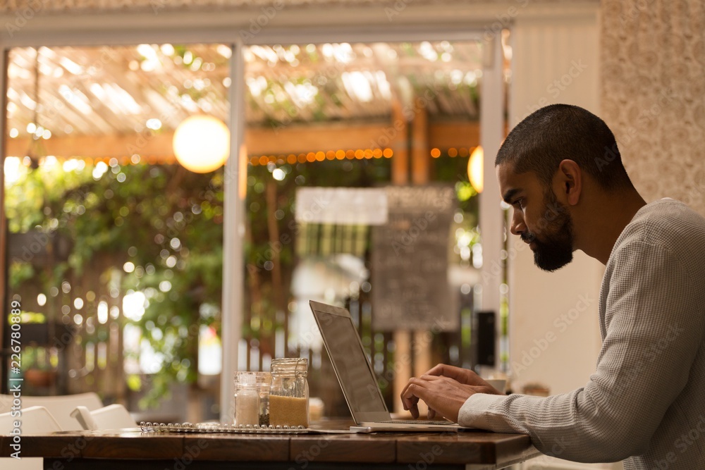 Man using laptop in cafe Man using laptop in cafe