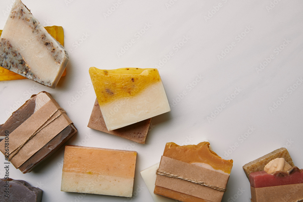 top view of various handmade soap pieces on white marble surface - obrazy, fototapety, plakaty 