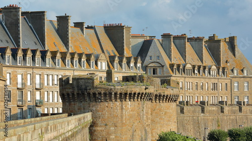 Traditional house facades with chimneys and roofs, located inside the walled city of Saint Malo, with the ramparts in the foreground, Saint Malo, Brittany, France