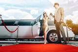 Driver helping VIP woman or star out of limo on red carpet to a reception 