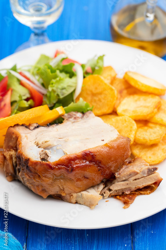 roasted piglet with potato chips and orange on white plate