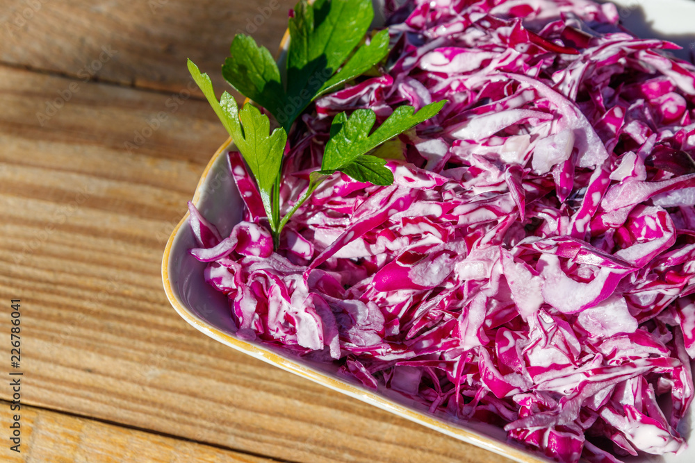 Red cabbage salad with onion and mayonnaise on wooden table. Top view