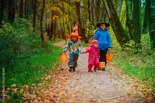 kids in halloween costume trick or treating in autumn nature