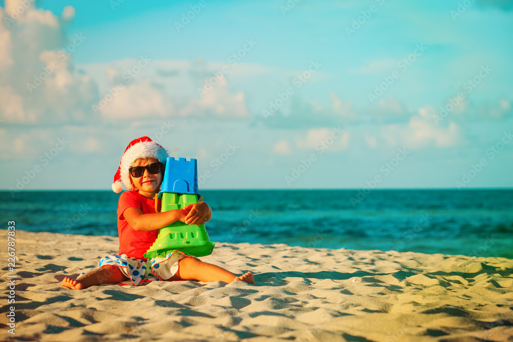 happy little girl play with sand and toys on beach at christmas happy little girl play with sand and toys on beach at christmas