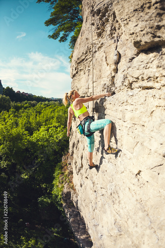 The woman climbs the rock.