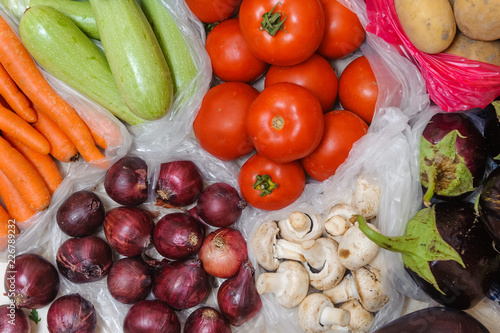 Various fruits and vegetables in plastic bags are on the floor in the house. Bought on the market