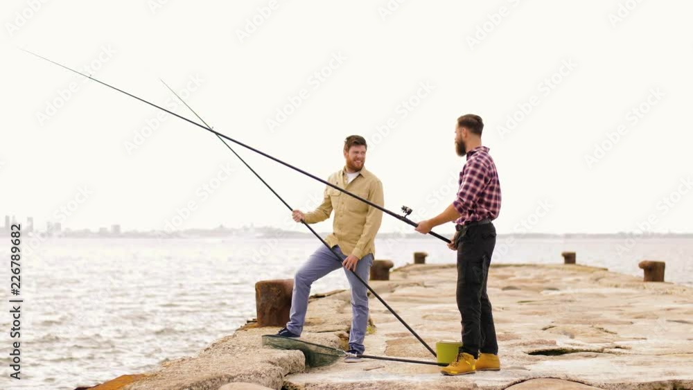 leisure and people concept - happy friends with fishing rods on pier leisure and people concept - happy friends with fishing rods on pier