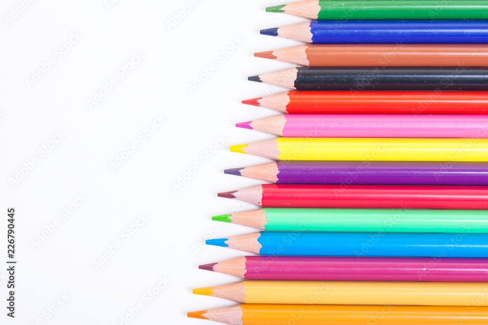 Colorful wooden pencils on isolated white background. A drawing tool. Objects for creativity. Colored pencils on a light background in a diagonal line. Colorful wooden pencils on isolated white background. A drawing tool. Objects for creativity. Colored pencils on a light background in a diagonal line.