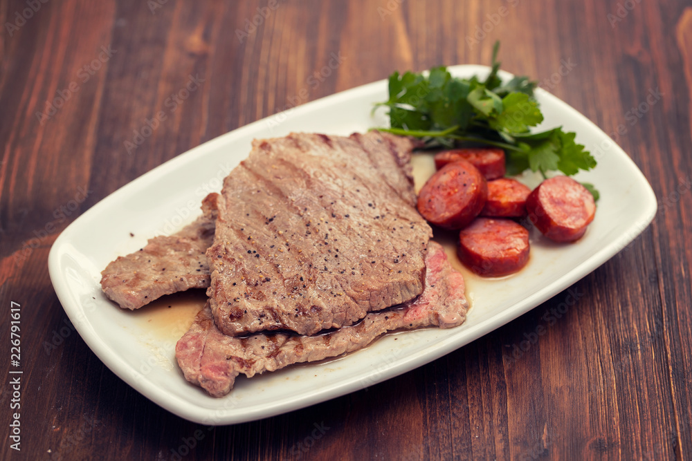 grilled meat with smoked sausage on white dish grilled meat with smoked sausage on white dish
