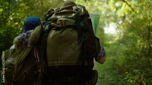 Travelers with backpacks on hiking in the green forest