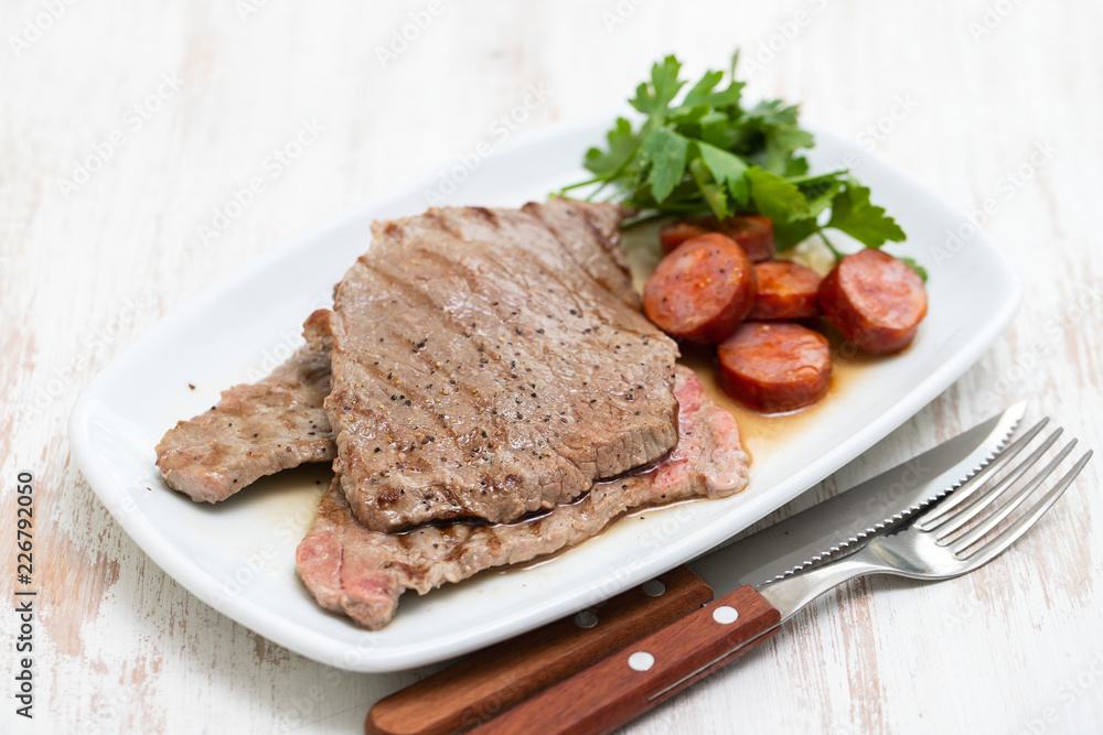 grilled meat with smoked sausage on white dish grilled meat with smoked sausage on white dish