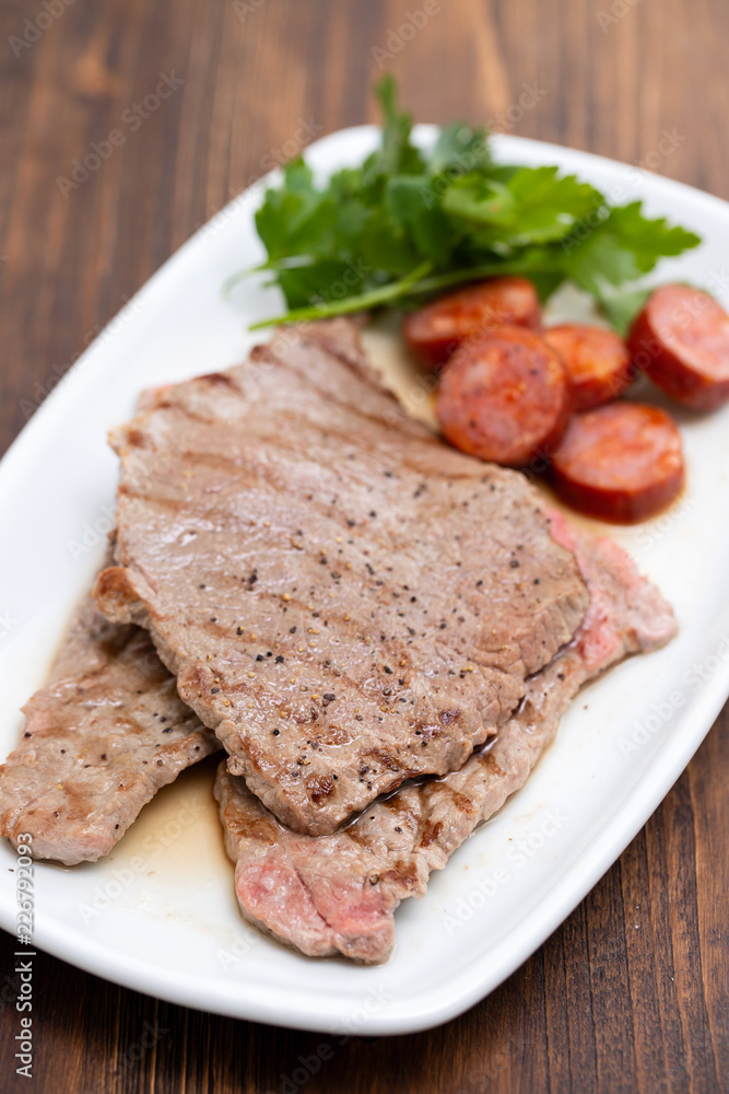 grilled meat with smoked sausage on white dish grilled meat with smoked sausage on white dish