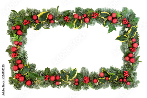 Christmas decorative background border with red bauble decorations, holly, fir, mistletoe and ivy isolated on white background. Festive theme.