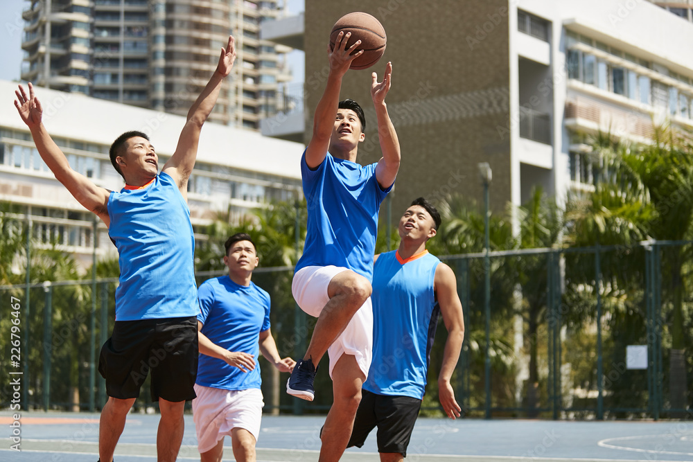 Obraz premium young asian adults playing basketball