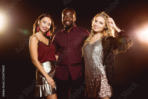 handsome african american man hugging two attractive women on black with backlit