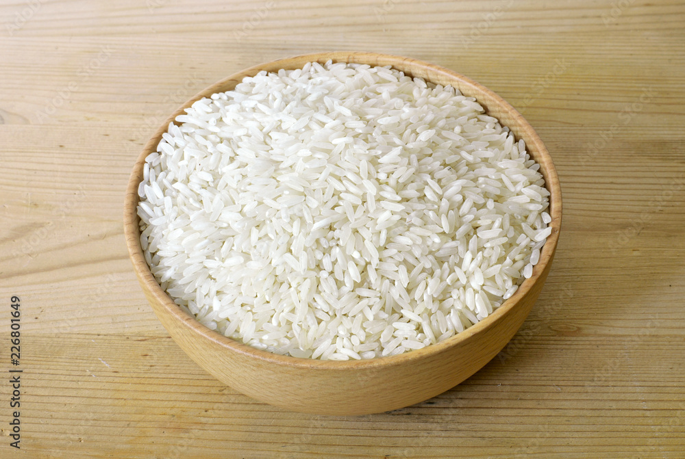 Raw, parboiled rice in a wooden bowl. Rice dish on a wooden table, diet or healthy eating scene. Raw, parboiled rice in a wooden bowl. Rice dish on a wooden table, diet or healthy eating scene.