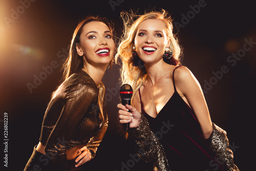 attractive cheerful women singing with microphone in karaoke