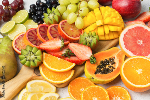 Fototapeta Naklejka Na Ścianę i Meble -  Healthy colourful fruits in rainbow colours, strawberries, mango, grapes, bananas, grapefruit on the off white table, side view, selective focus