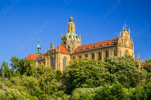 Obraz na płótnie Monumental monastery of Benedictines in Kladruby, Czech Republic, Europe from 12th century standing on hill, includes church of All Saints, red roof, green foreground, sunny summer day, blue sky w salonie