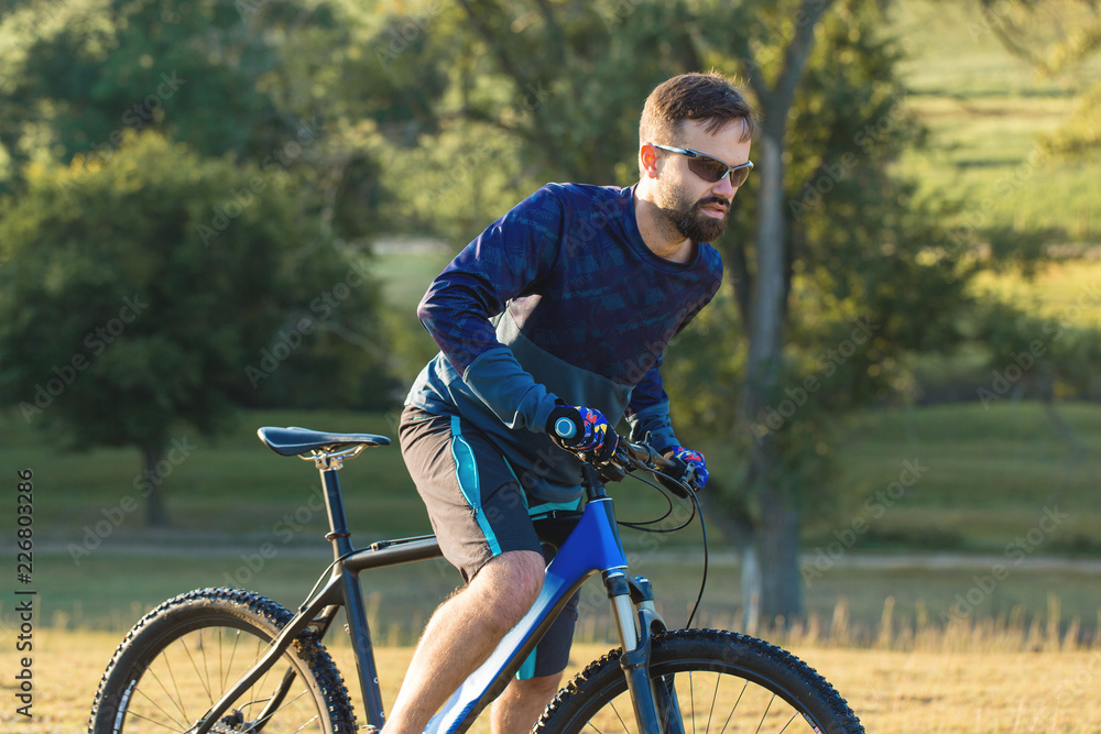 A cyclist rides the hills, Beautiful portrait of a guy on a blue bicycle A cyclist rides the hills, Beautiful portrait of a guy on a blue bicycle