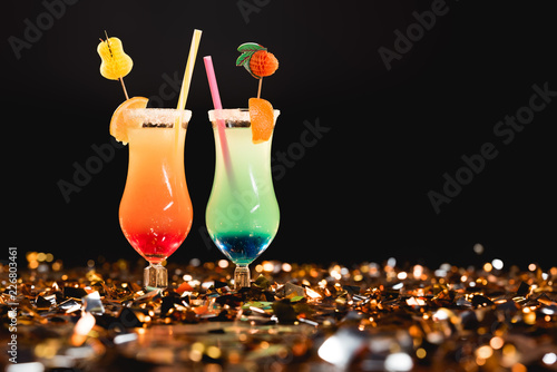 sweet cocktails with straws on golden confetti with copy space