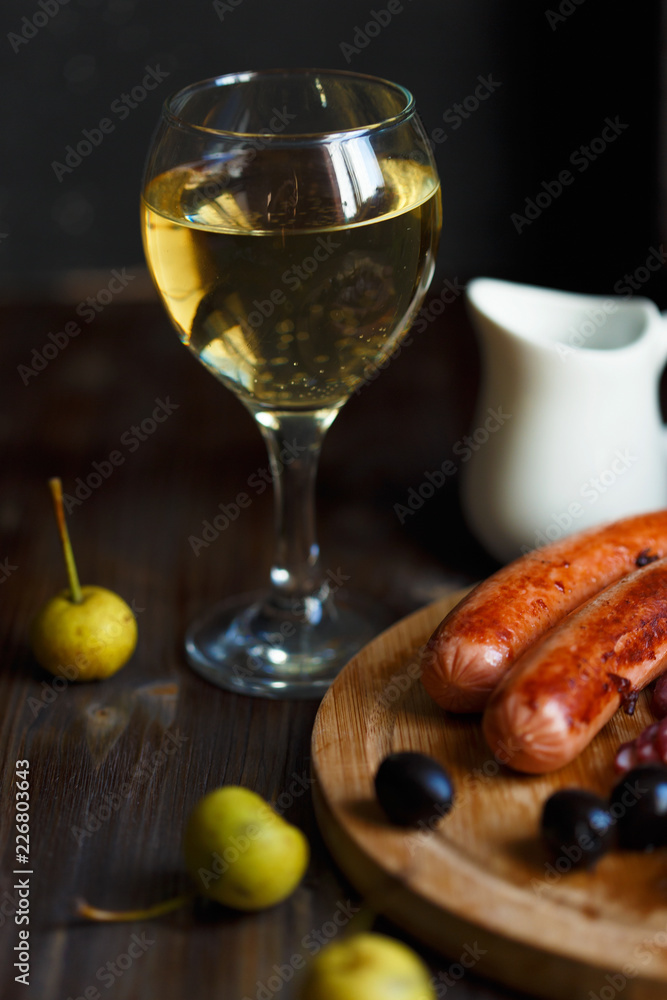 glass of homemade pear wine with a snack. Grilled sausages, cheese, olives. Menu and restaurant concept. glass of homemade pear wine with a snack. Grilled sausages, cheese, olives. Menu and restaurant concept.
