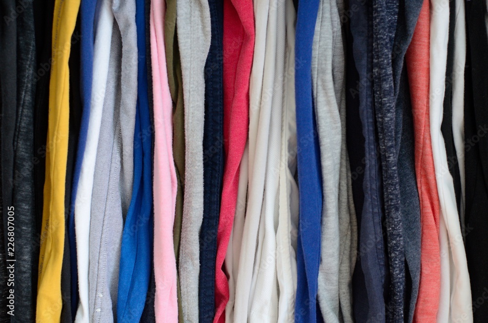 The colorful photo of messy clothes hanging in wardrobe that taking as background.