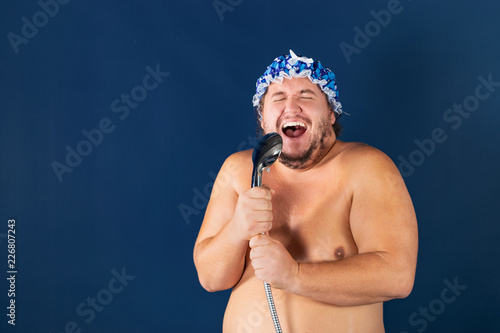 Funny fat man in blue cap sing in the shower