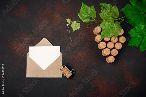Gape bunch of cork with leaves, envelope and letter on rusty background.