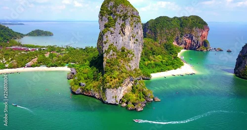 Boats Navigating Around Dramatic Rock Island in Tropical Bay with Beach and Multiple Islands in Background - Phra Nang Bay, Thailand photo