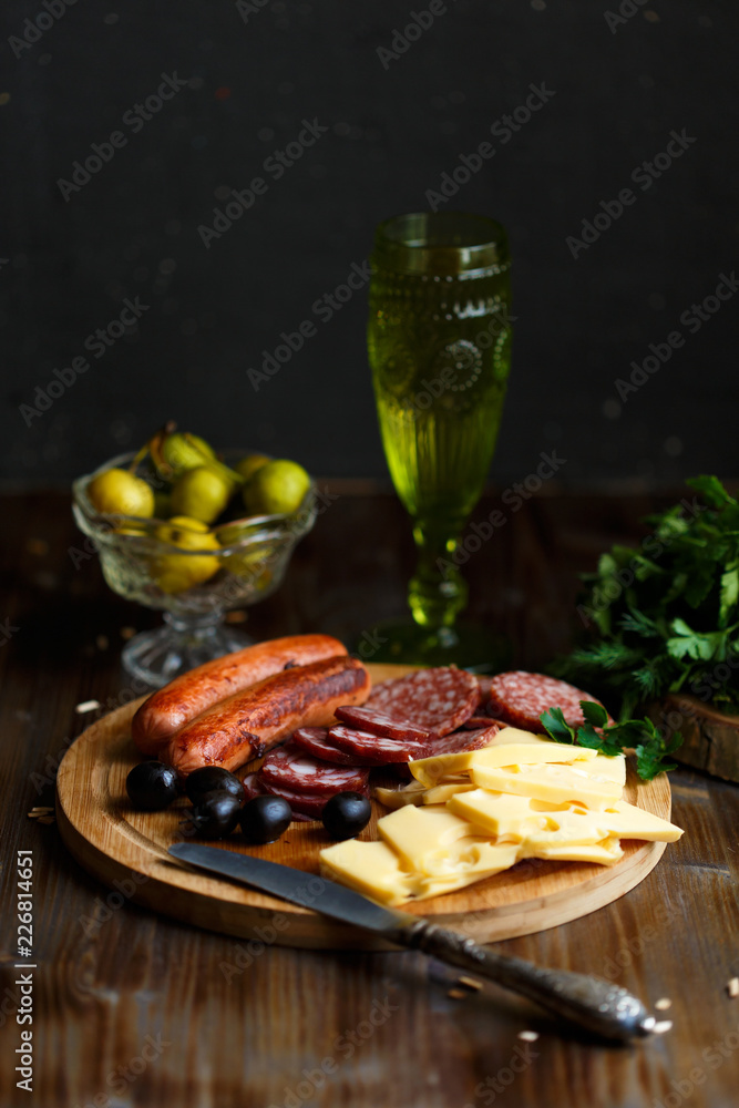 Aperitif table Meat snack, fried sausages, cheese, salami, olives and a glass of wine on a dark table. restaurant concept Aperitif table Meat snack, fried sausages, cheese, salami, olives and a glass of wine on a dark table. restaurant concept