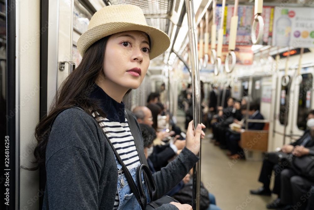 a female traveler wearing a straw hat taking MRT a female traveler wearing a straw hat taking MRT
