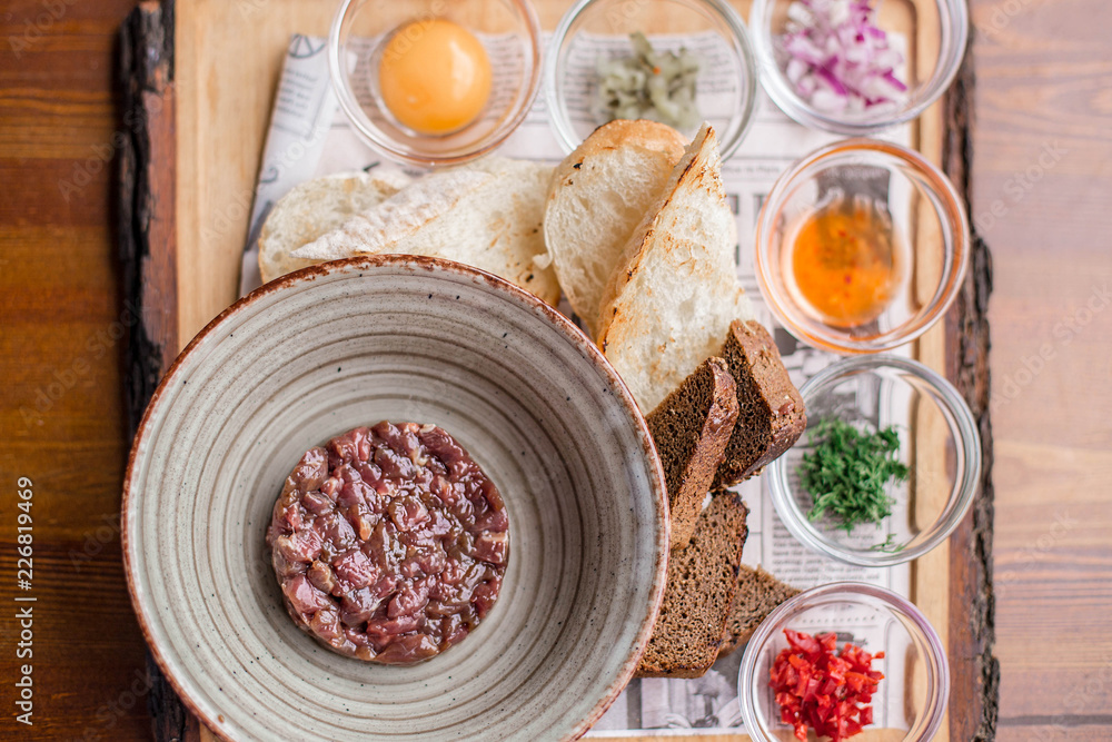 Beef tartar with egg, onion, and spices on the plate in the restaurant. Beef tartar with egg, onion, and spices on the plate in the restaurant.