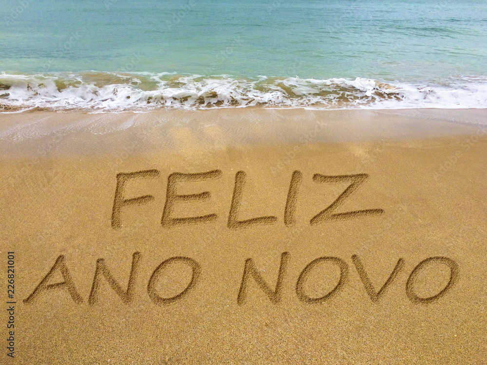 Fototapeta premium Happy new year written in the sand on a beautiful Brazilian beach (translation portuguese: happy new year).