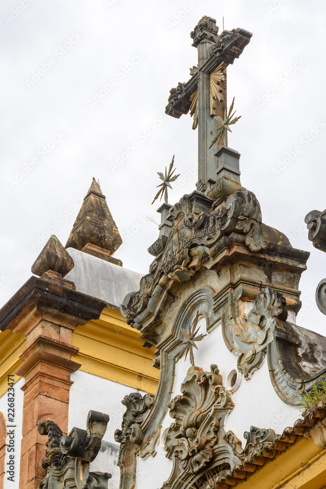 Baroque style crucifix on top of ancient and historical church in the city of Sabara in Minas Gerais